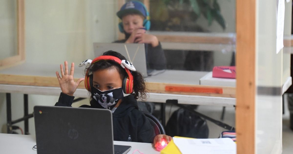 Students separated by plastic barriers follow along remotely with their regular schoolteacher's online live lesson at the STAR Eco Station Tutoring and Enrichment Center in Culver City, California, on Sept. 10.