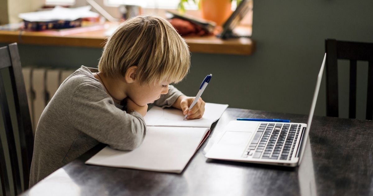 This stock image portrays a young boy taking notes at a laptop at home. The Ann Arbor Board of Education released a statement Friday that moving forward, the board would make a recommendation to modify the current plan to allow schooling to remain virtual until the end of the school year.