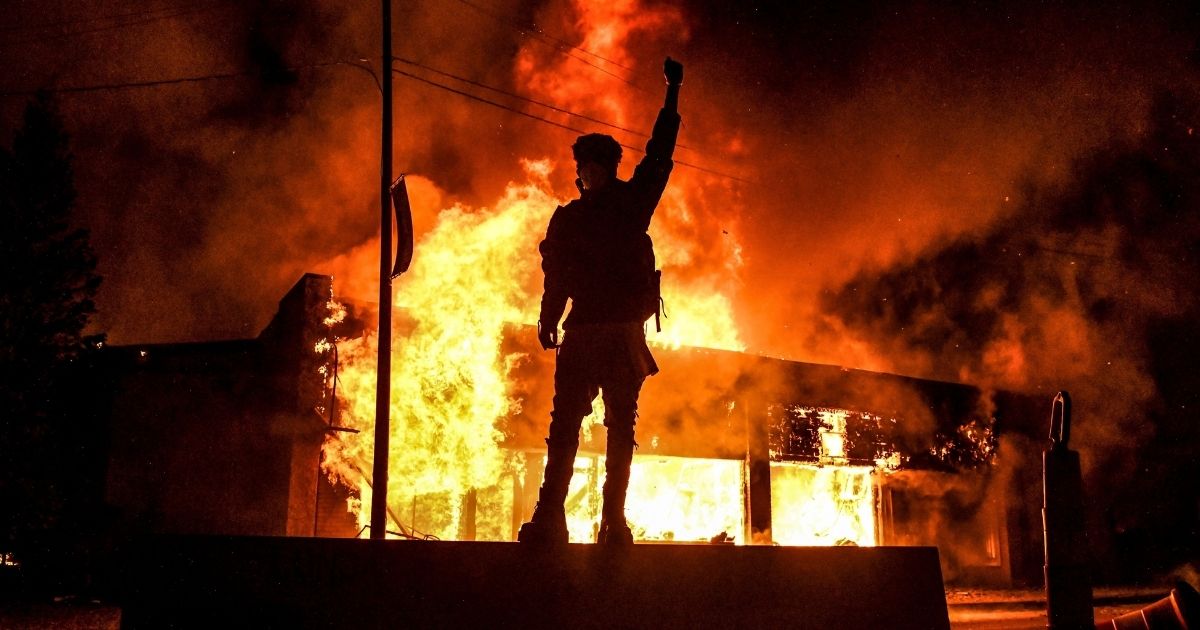 A protester reacts standing in front of a burning building set on fire during a demonstration in Minneapolis, Minnesota, on May 29, 2020.