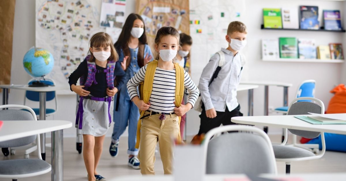A group of schoolchildren wearing masks is pictured in the stock image above.
