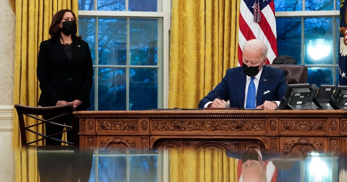 President Joe Biden signs executive orders directing immigration actions for his administration as Vice President Kamala Harris looks on in the Oval Office of the White House on Feb. 2, 2021.