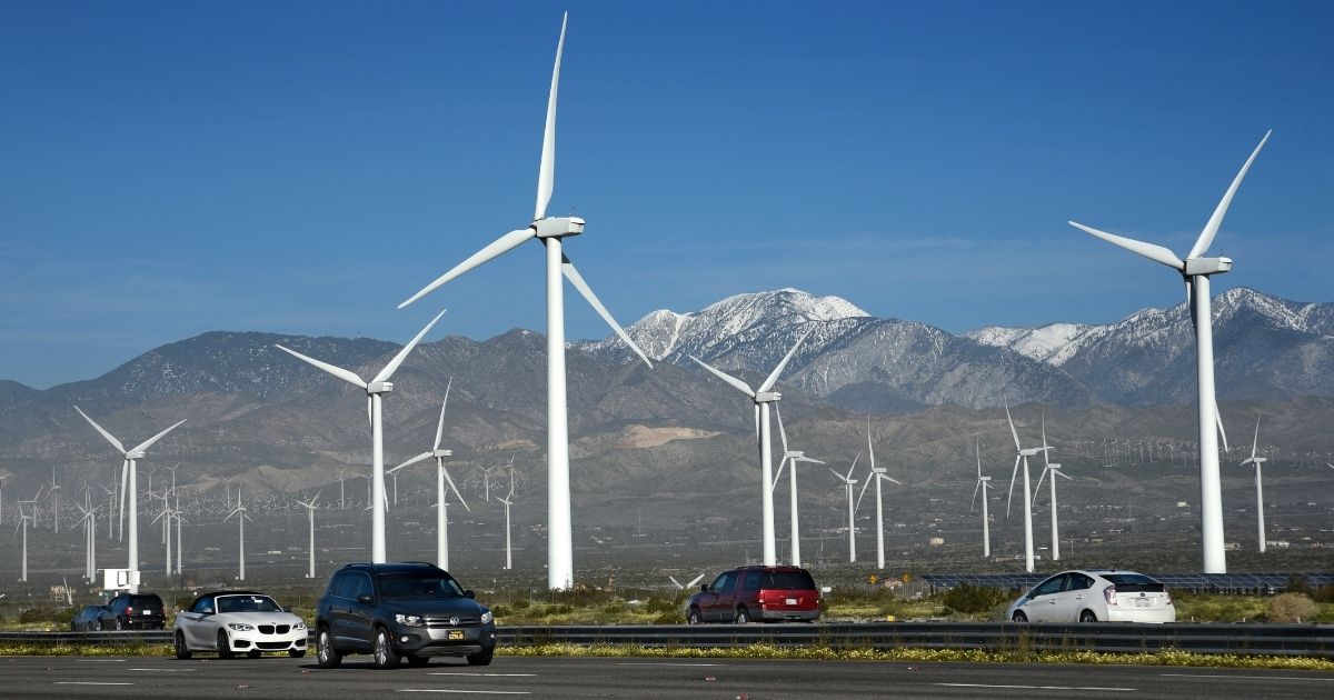Automobiles travel along Interstate 10 as wind turbines generate electricity at the San Gorgonio Pass Wind Farm near Palm Springs, California.