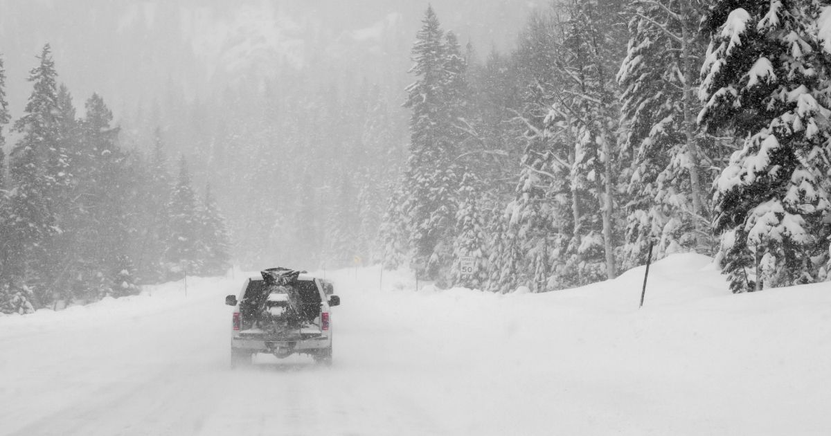 A pickup truck drives in the snow in the above stock image.