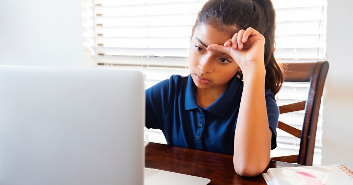 A girl sits in front of a computer in this stock image.