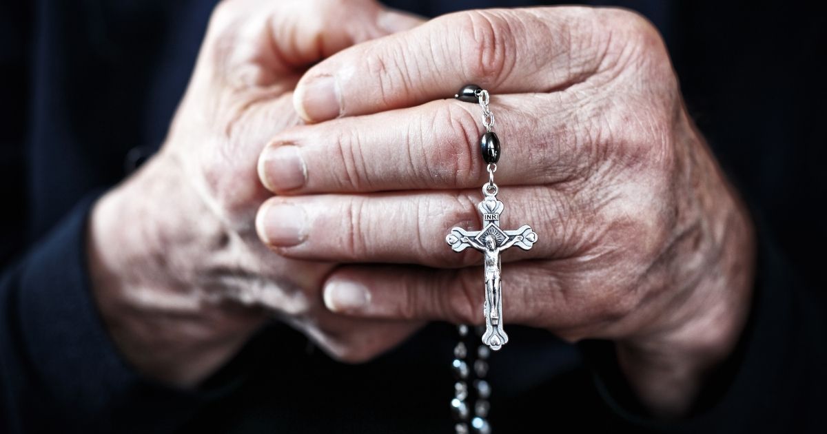 A nun prays a rosary in the above stock image.