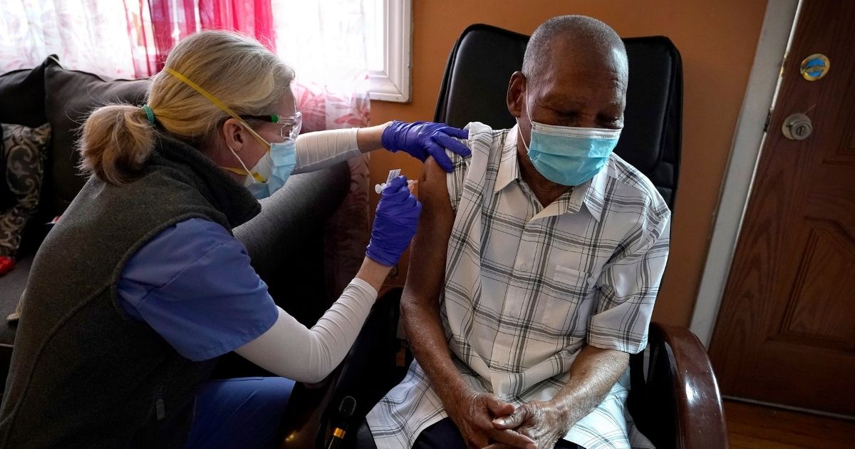 Geriatrician Megan Young, left, gives Edouard Joseph, 91, a COVID-19 vaccination on Feb. 11, 2021, at his home in the Mattapan neighborhood of Boston.