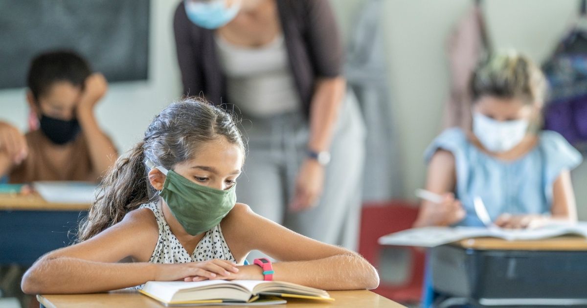 A girl reads a book in a classroom in this stock image.