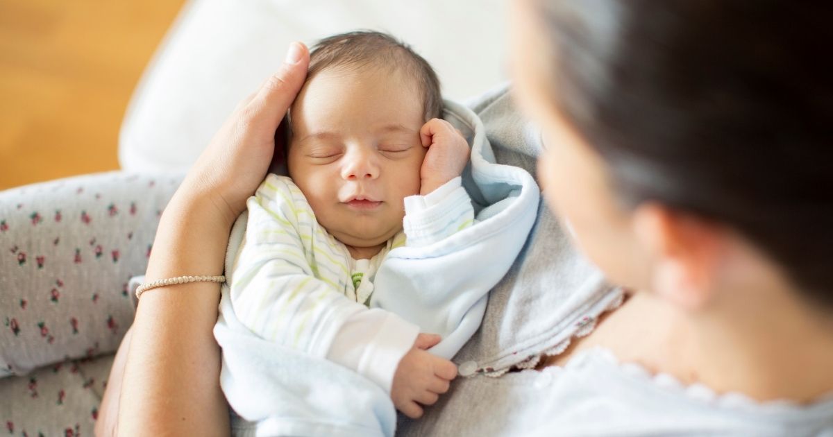 A mother holds a baby in the above stock image.
