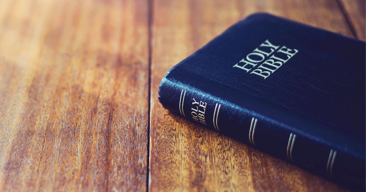 A Bible is pictured on a wooden table.