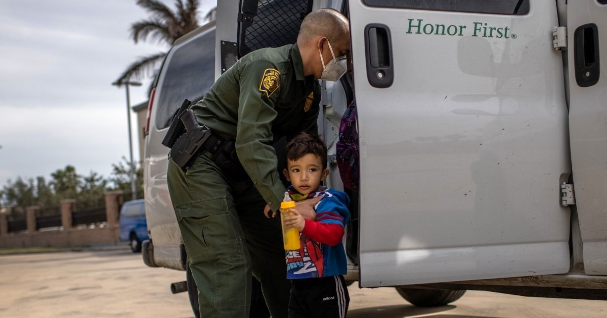 A Border Patrol agent delivers a young asylum seeker and his family to a bus station on Feb. 26, 2021, in Brownsville, Texas.