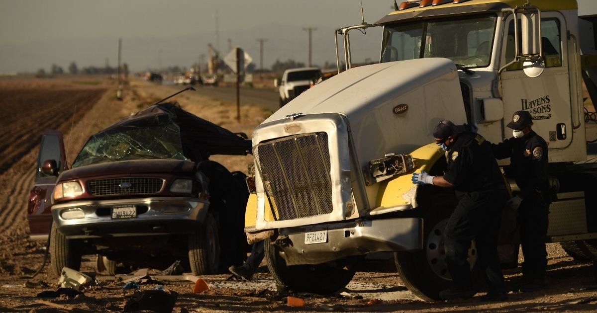 Investigators look over the scene of a crash between an SUV and a semi-truck full of gravel near Holtville, California on Tuesday.
