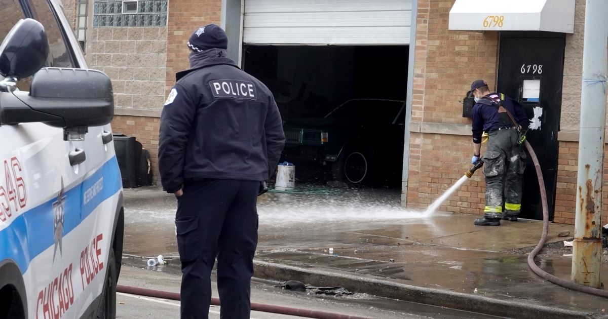 A Chicago firefighter hoses blood off of the sidewalk following a shooting at a tow company garage where at least 15 people were reported to have been shot, two fatally, on Sunday.