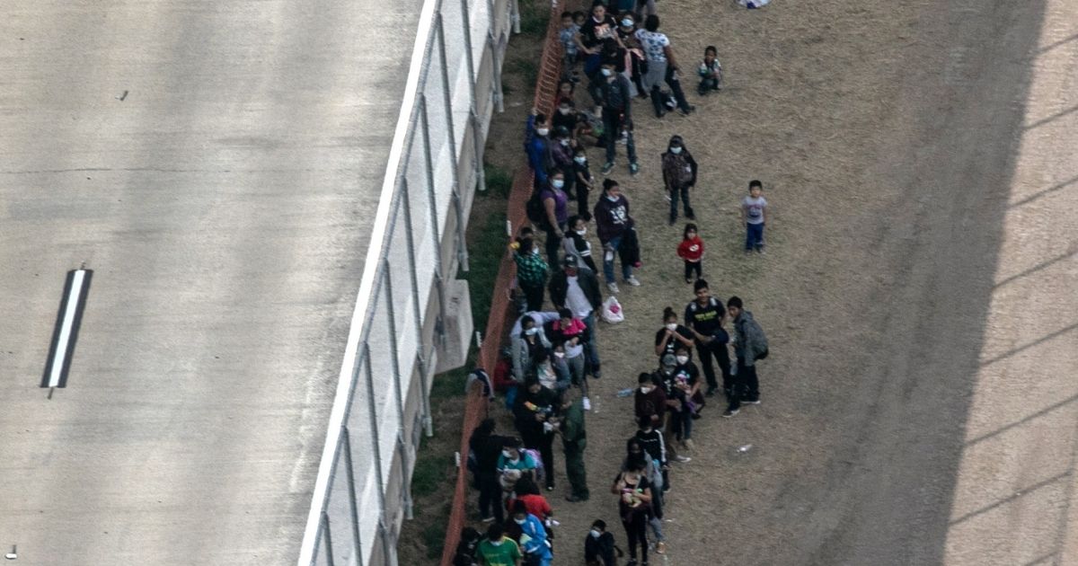 Migrants and asylum seekers stand under an outdoor U.S. Border Patrol processing center under a bridge, as seen from a Texas Department of Public Safety helicopter near the U.S.-Mexico Border on Tuesday near Mission, Texas.
