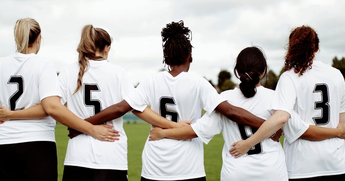 Members of a girls soccer team huddle together.