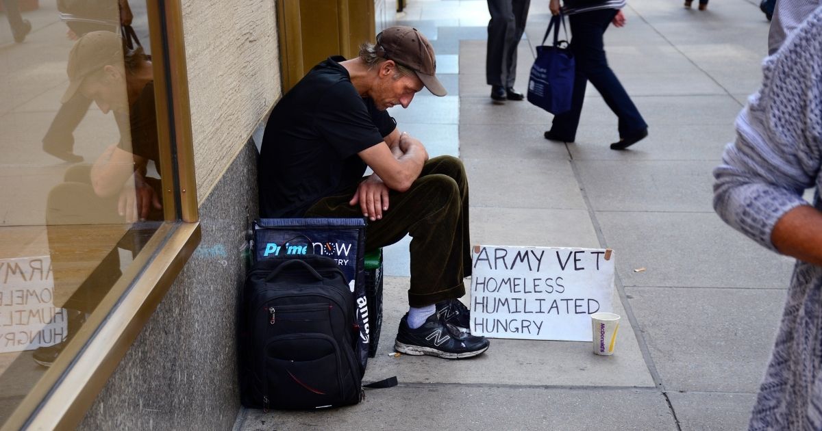 A man with a sign identifying himself as a homeless Army veteran asks for money as he sits on a New York City sidewalk.