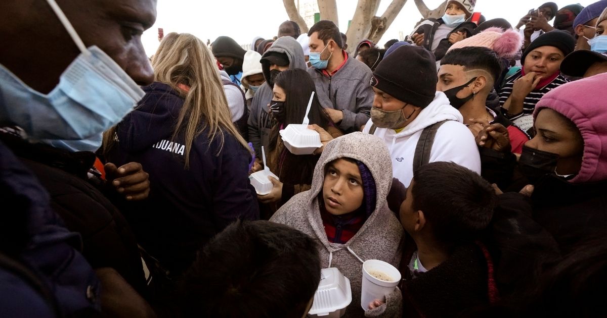 Asylum seekers receive food as they wait for news of policy changes at the border on Feb.19, 2021, in Tijuana, Mexico.
