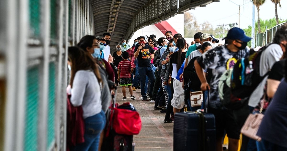 Migrants wait in line to cross the border at the Gateway International Bridge from Matamoros, Mexico, to Brownsville, Texas, on Monday.