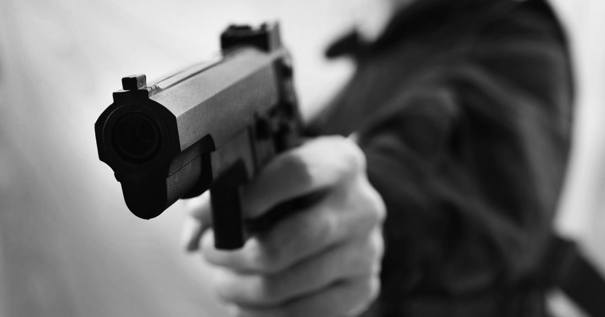 A man holds a pistol.