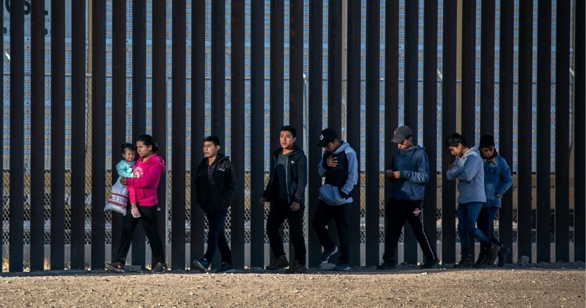 Undocumented immigrants walk along the U.S.-Mexico border wall after they ran across the shallow Rio Grande into El Paso on Wednesday in Ciudad Juarez, Mexico.