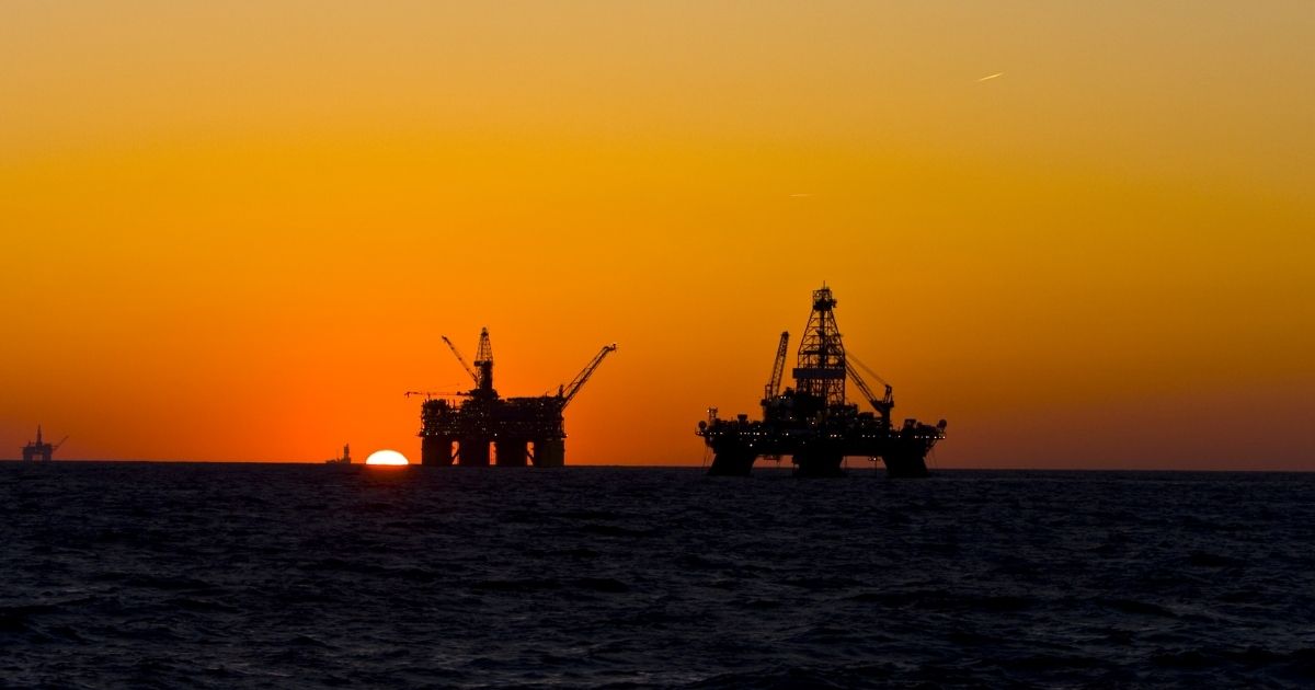 Oil platforms are silhouetted at sunset in the Gulf of Mexico.