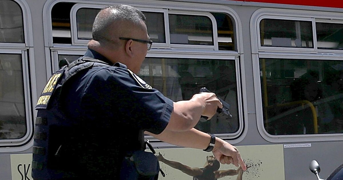 A police officer draws his gun during a confrontation with a suspect in San Francisco on June 21, 2017.