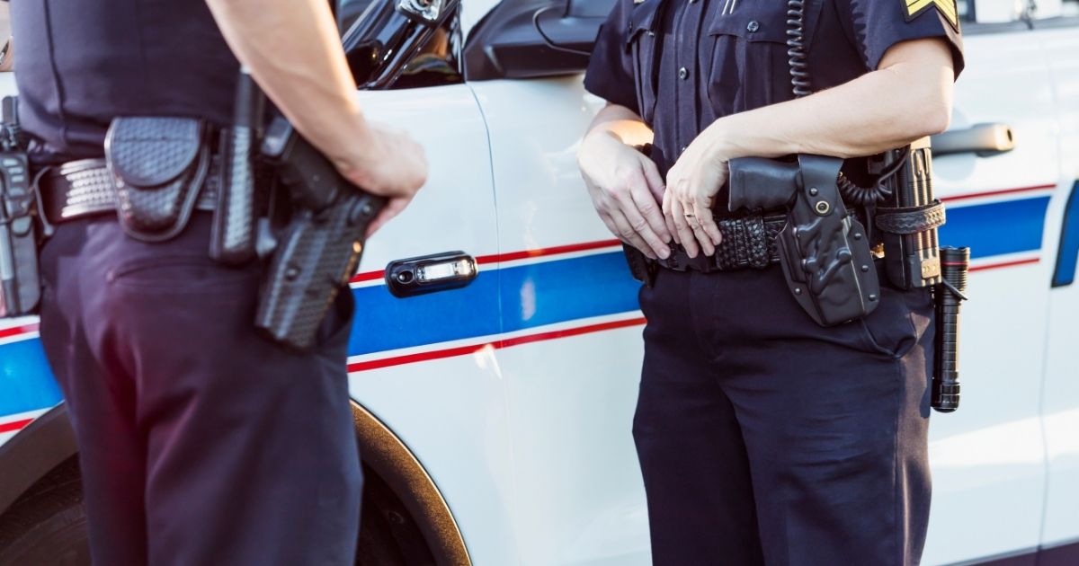 The above stock photo shows police officers standing beside a squad car having a conversation.