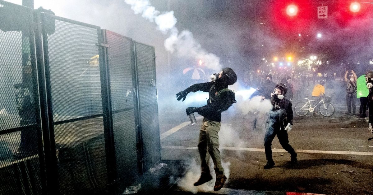 A demonstrator lobs a projectile at federal officers guarding the Mark O. Hatfield U.S. Courthouse in Portland, Oregon, during a left-wing riot July 24.