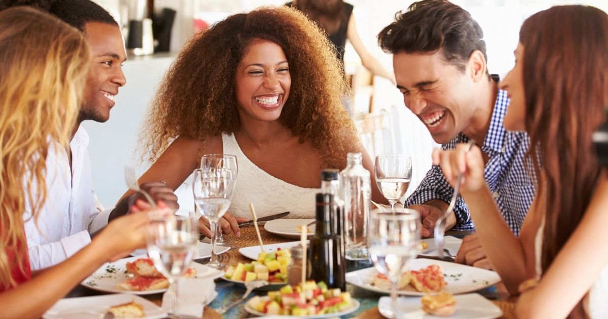 A group of people enjoy a meal at a restaurant in the stock image above.