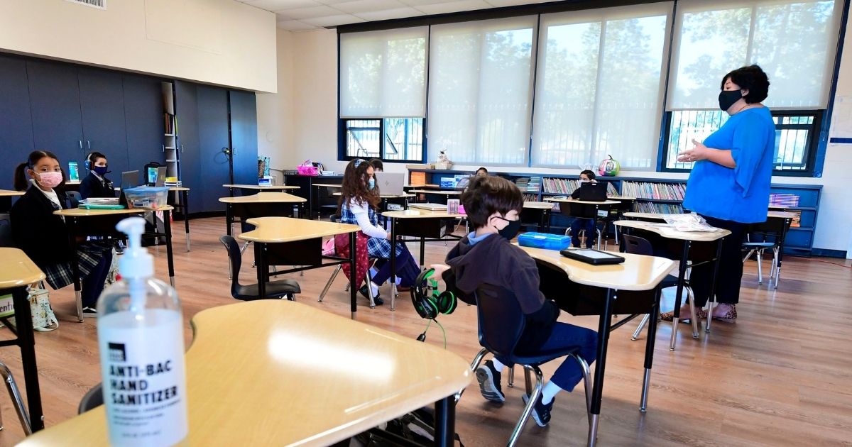 Students in a classroom listen to their teacher