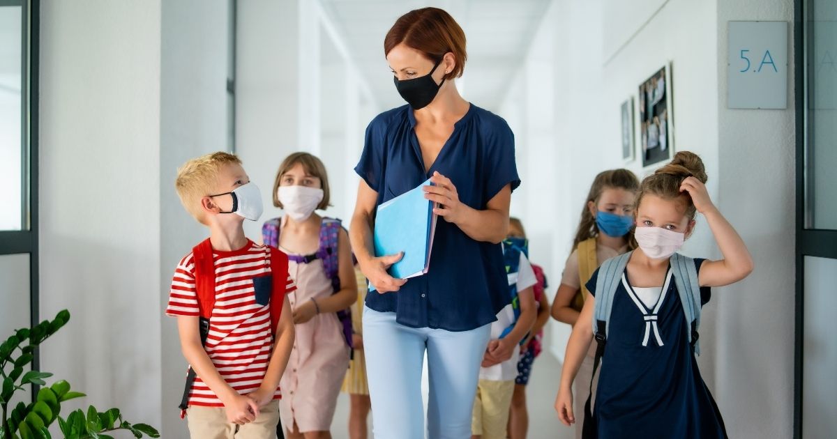 The above stock image shows a teacher and children going back to school after the Coronavirus quarantine.