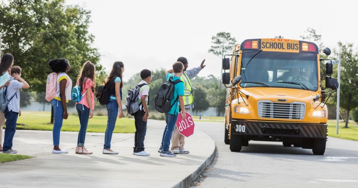 Children wait to board a school bus in a stock photo.