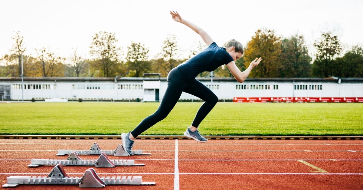 A female athlete runs on a track in this stock image.