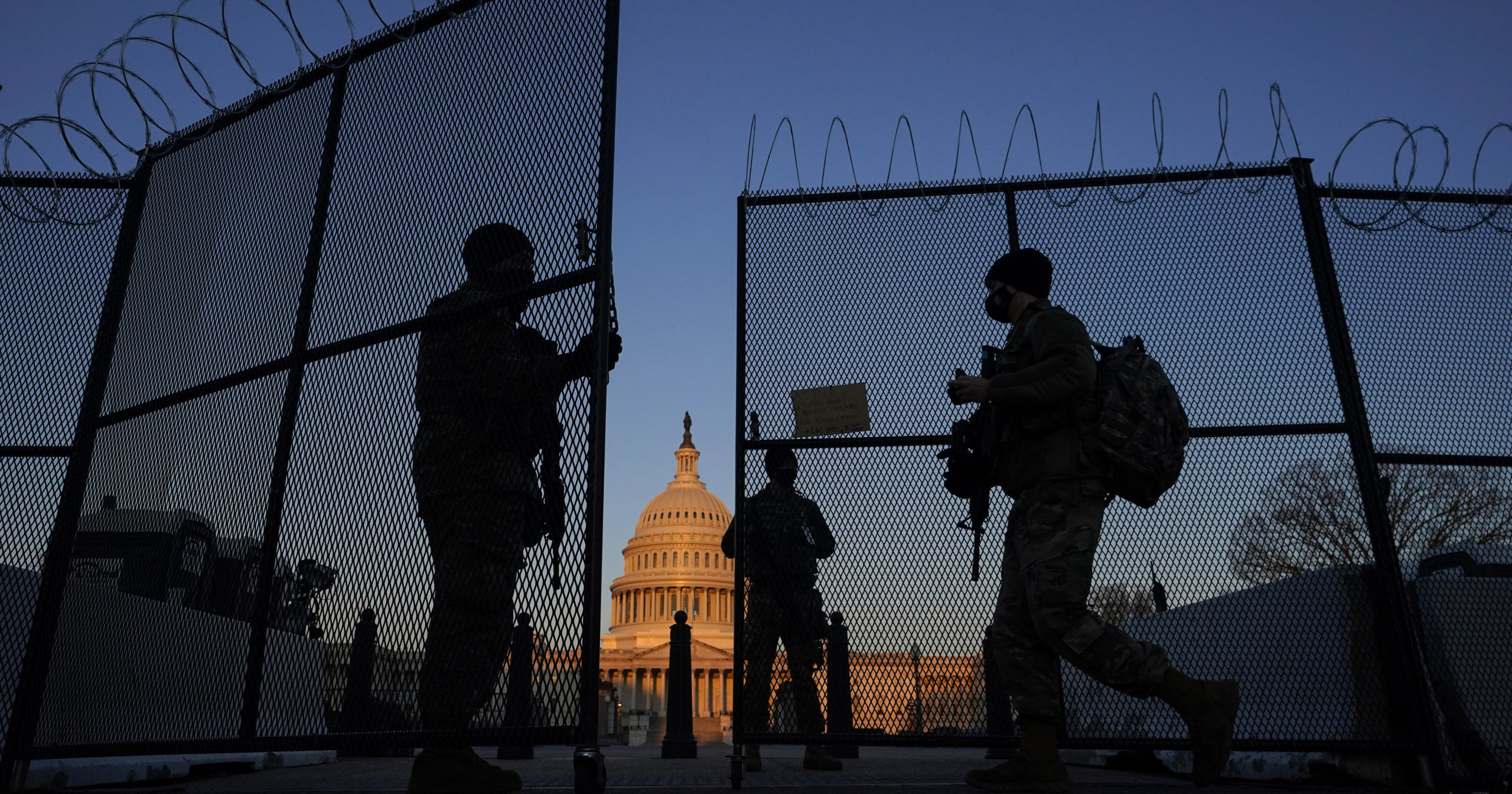 National Guard soldiers open a gate of the razor wire-topped perimeter fence around the Capitol to allow a colleague in at sunrise in Washington on March 8, 2021.