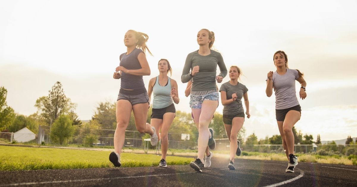 Girls run on a track in this stock image.