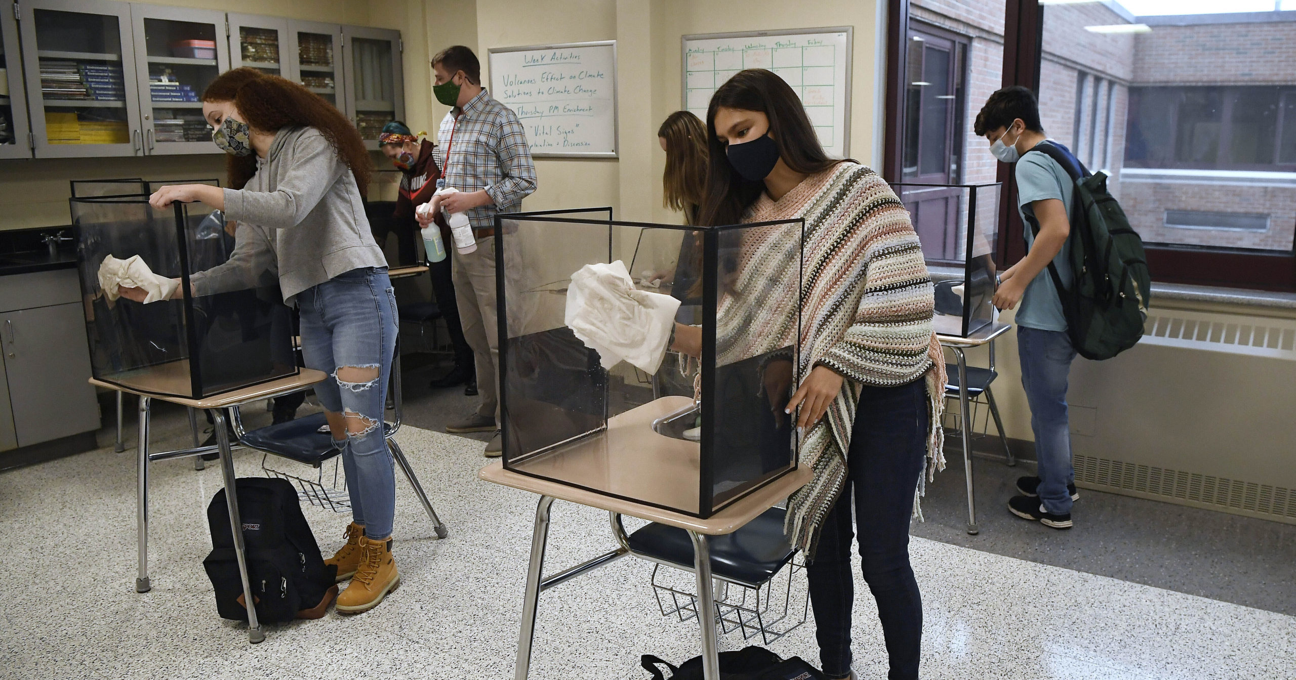 Students clean their work areas at the end of class at Windsor Locks High School in Windsor Locks, Connecticut, on March 18, 2021.