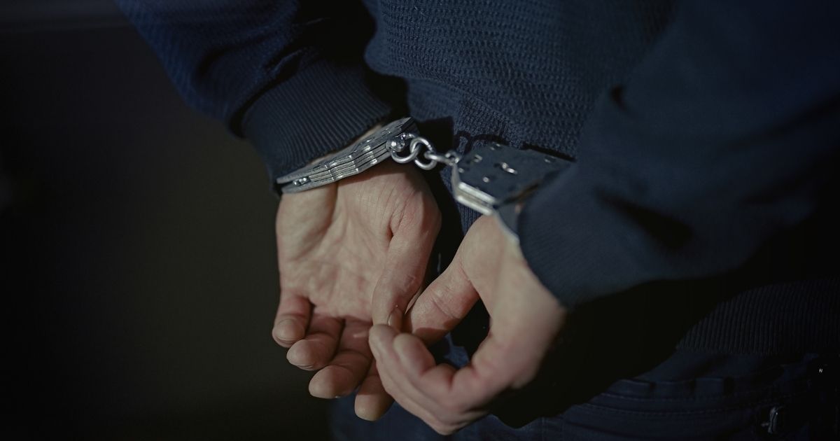 A man wearing handcuffs is seen in this stock image.