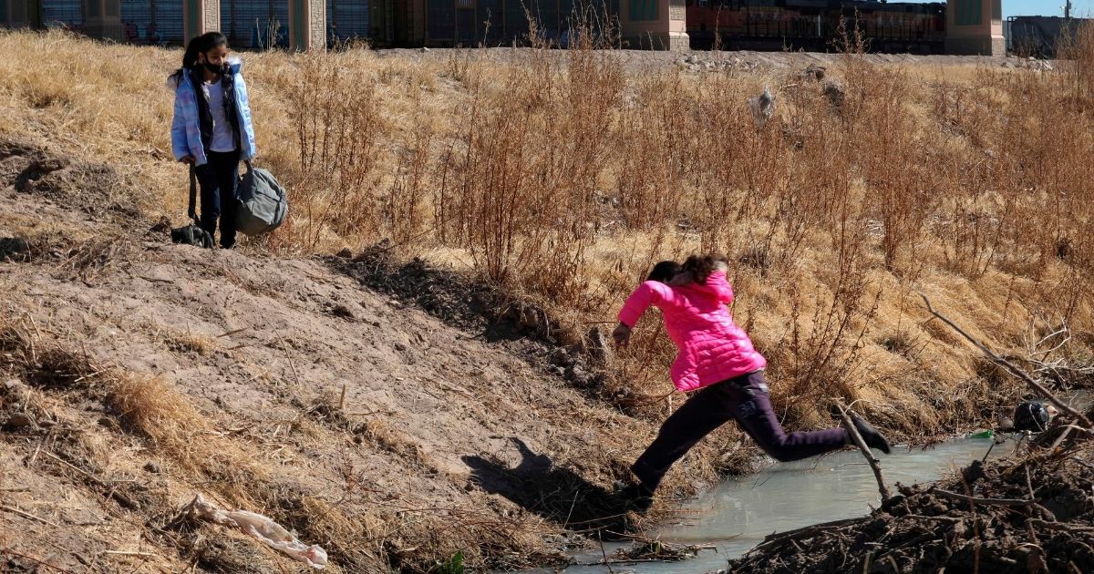 A migrant girl jumps to cross the Rio Bravo to get to El Paso, Texas, from Ciudad Juarez, Chihuahua state, Mexico, on Feb. 5, 2021.