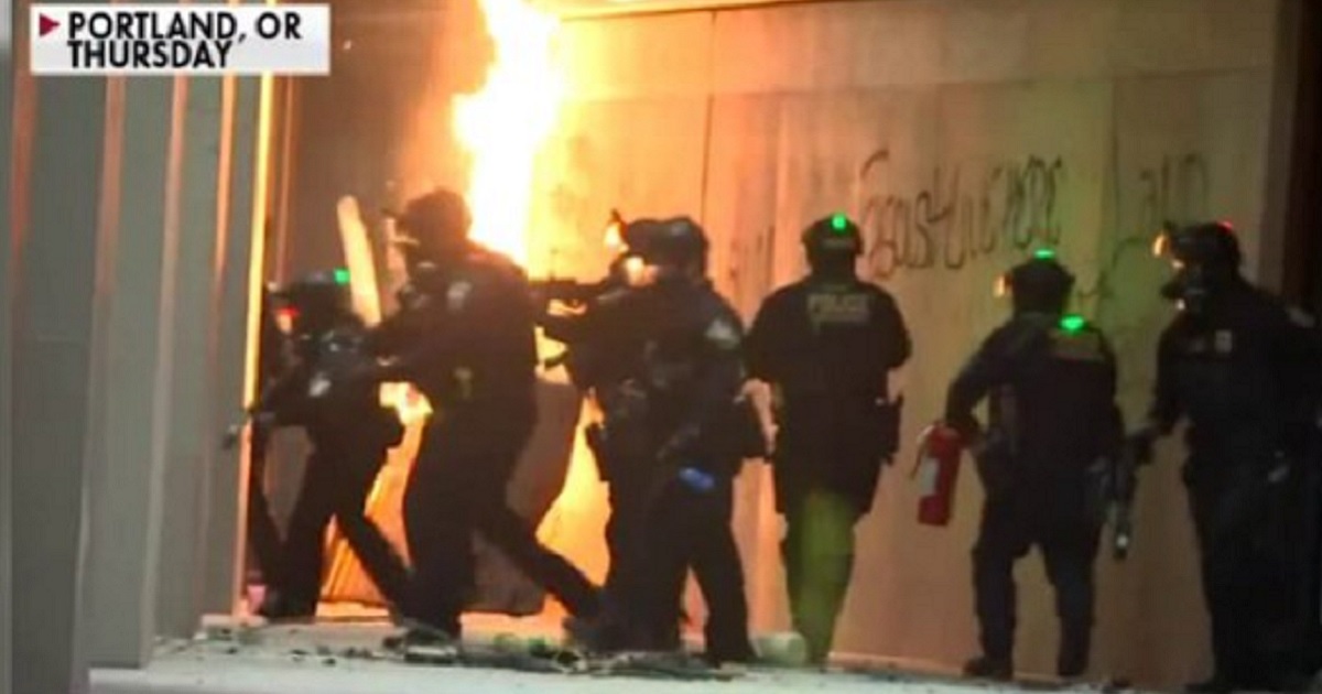 Armored law enforcement respond to a fiery riot scene Thursday in Portland, Oregon.