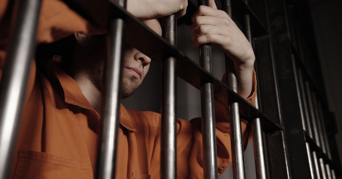 A man stands in a prison cell in the above stock image.
