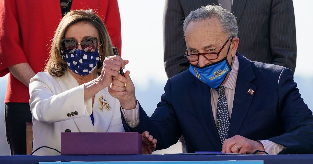 Speaker of the House Nancy Pelosi and Senate Majority Leader Chuck Schumer sign the $1.9 trillion coronavirus relief bill outside the US Capitol on March 10, 2021, in Washington, D.C.