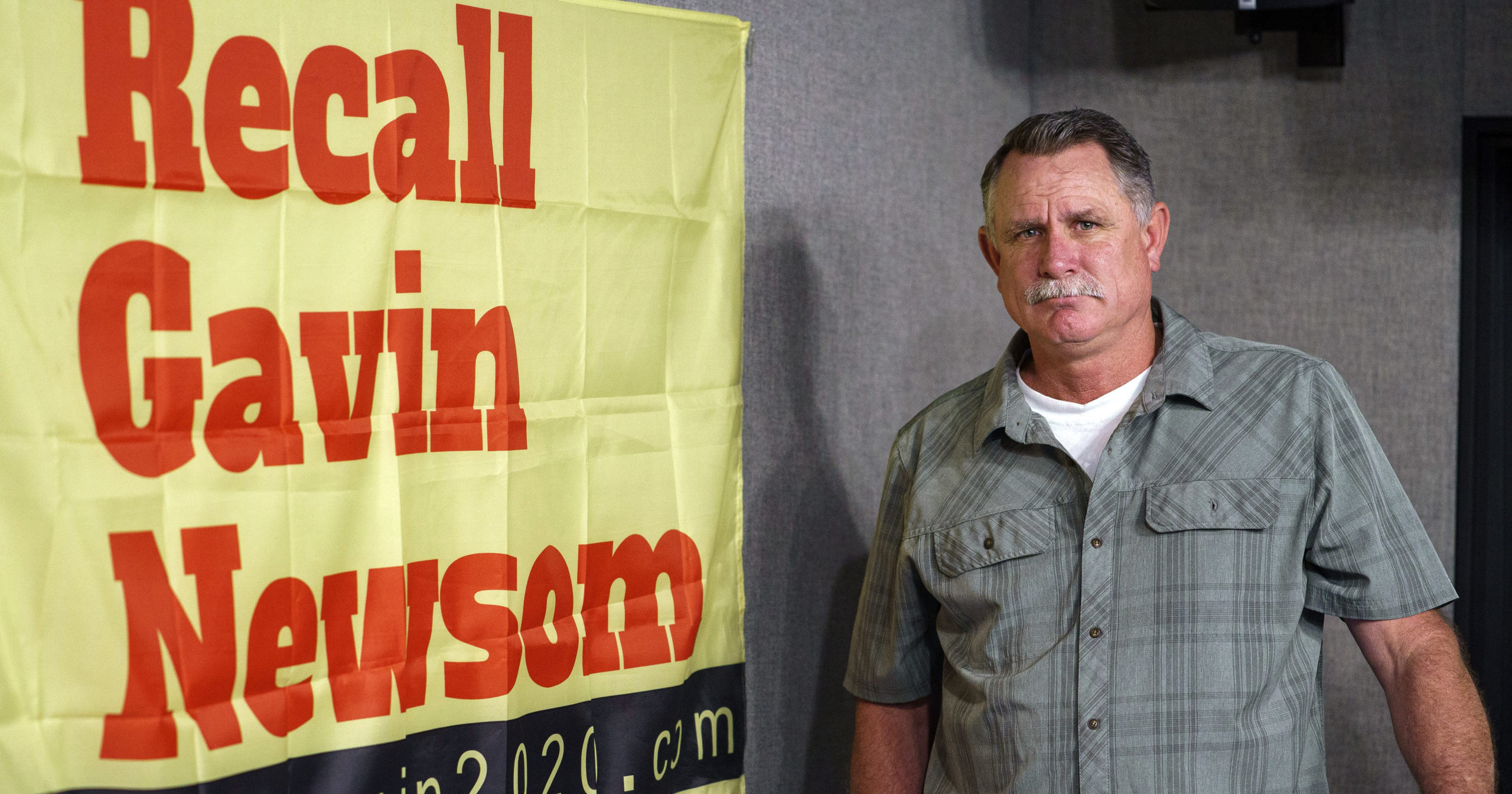 Orrin Heatlie, the main organizer of the campaign to recall California Gov. Newsom, poses with a banner before recording a radio program at the KABC radio station studio in Culver City, California, on March 27, 2021.