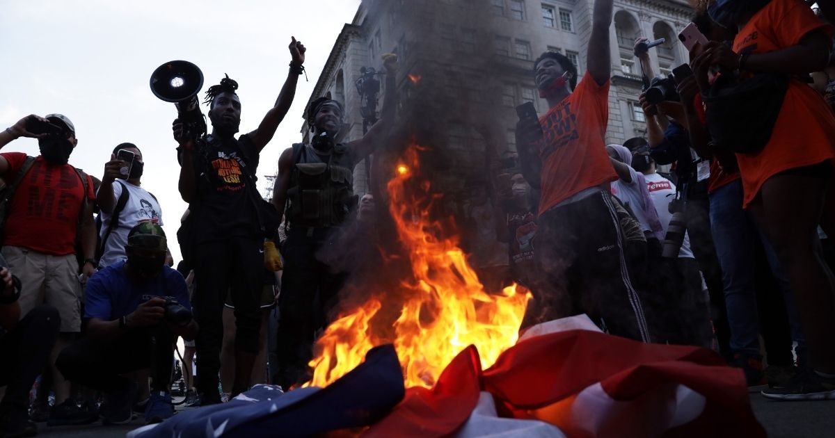 Rioters burn a U.S. flag at Black Lives Matter Plaza near the White House on July 4, 2020, in Washington, D.C.