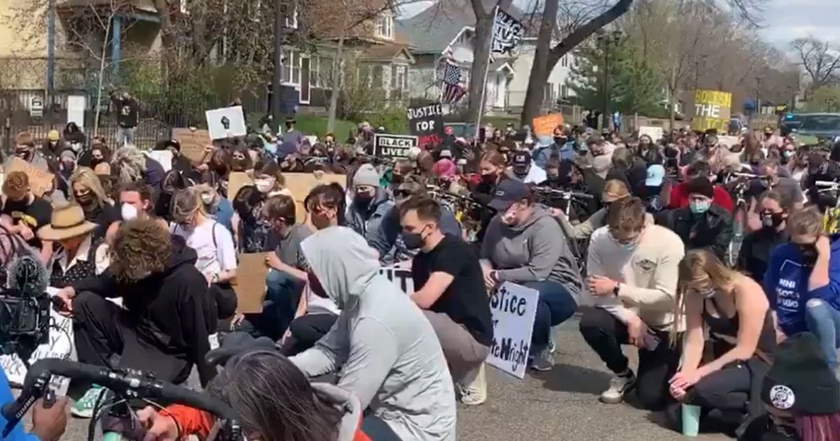 Protesters take a knee outside the Minnesota governor's mansion in St. Paul on Sunday amid reports of a shooting involving an officer in Burnsville, Minnesota.