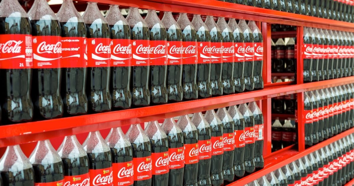 Bottles of Coca-Cola are pictured on shelves in the stock image above.