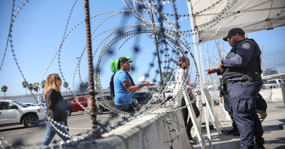 An Immigration and Customs Enforcement agents check pedestrians' documentation at the San Ysidro Port of Entry on Oct. 2, 2019, in San Ysidro, California.