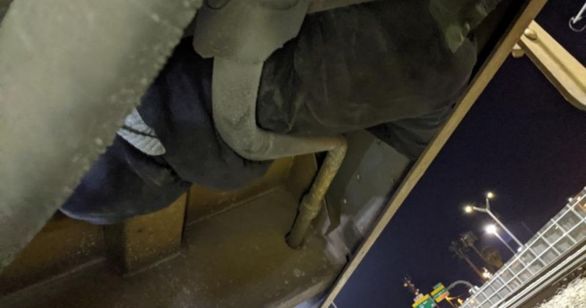 An illegal immigrant is seen in the undercarriage of a train car
