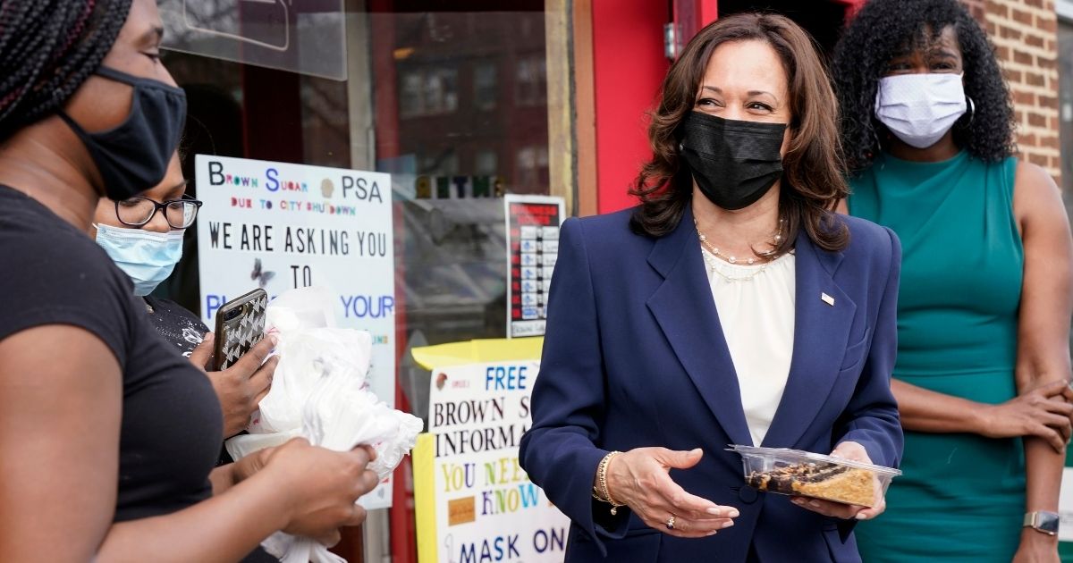 Kamala Harris holds a slice of cake outside Brown Sugar Bakery