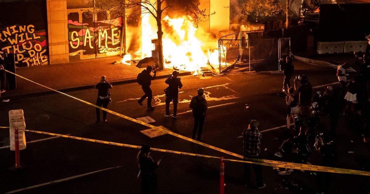 Protesters watch a structure fire, set following the police shooting of a homeless man on Friday in Portland, Oregon.