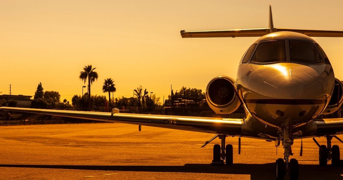 A private jet is parked on an airfield at sunset.