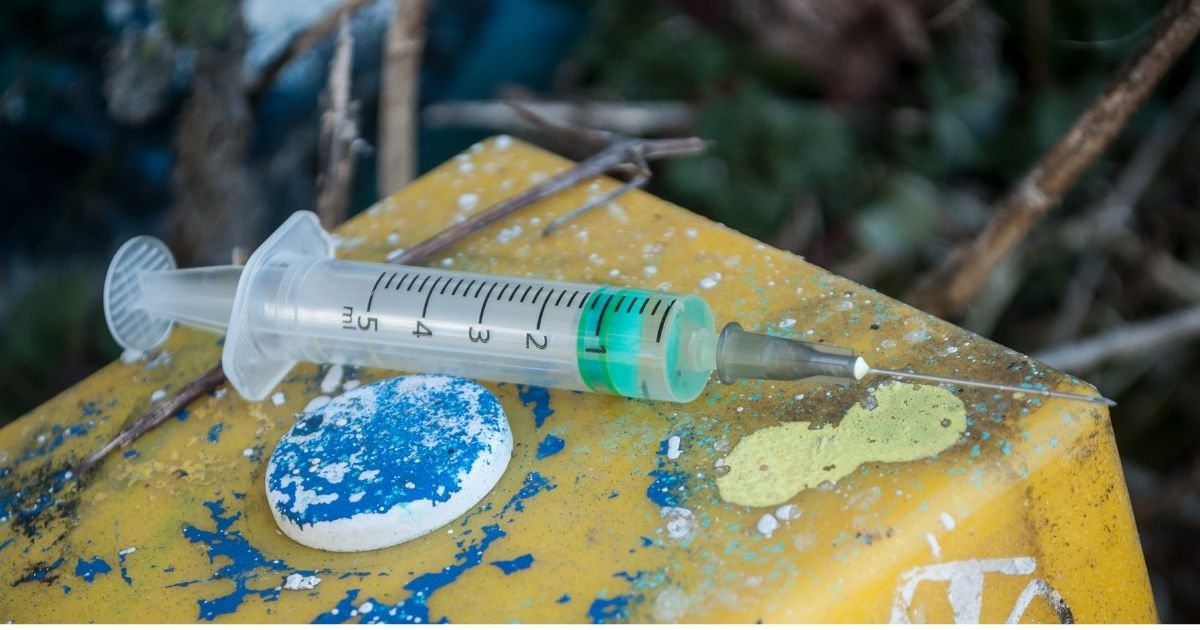 A discarded syringe on a dirty background.